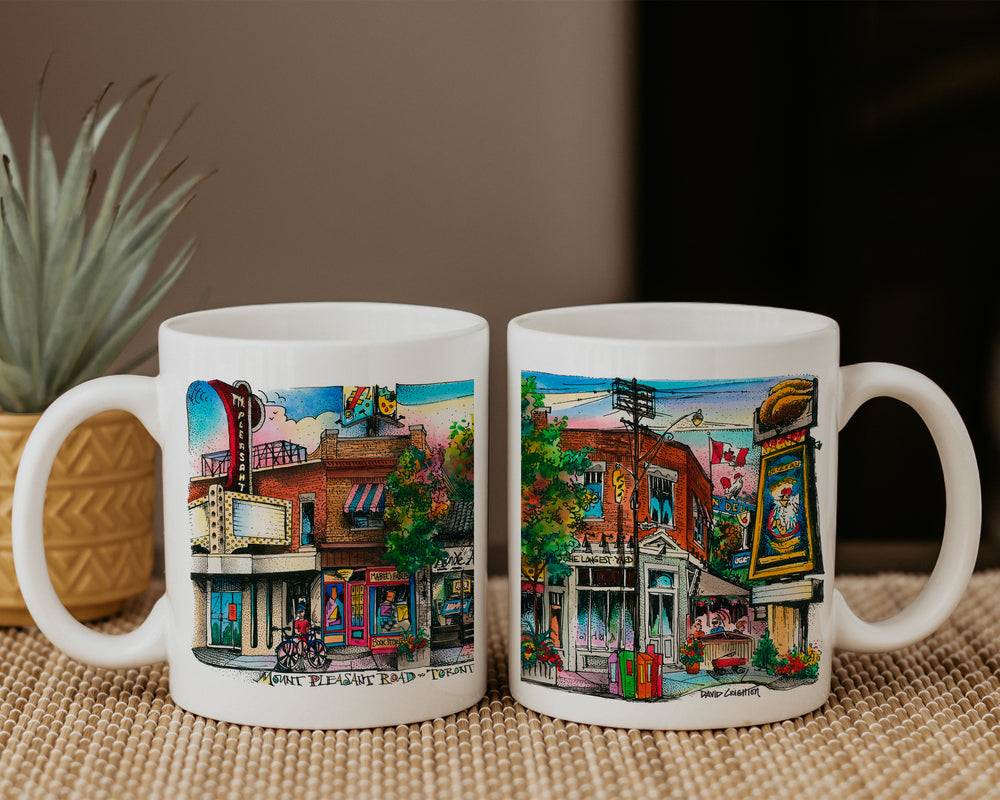 Two Mt. Pleasant Avenue Coffee Mugs side by side on a table featuring art by David Crighton
