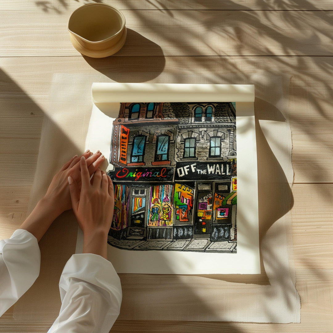 Beautiful illustration of Off The Wall from Toronto Art Shop on a wooden desk, dappled in sunlight. 