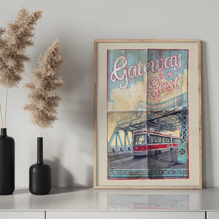 Gateway to the East Poster by Rob Croxford in a wooden frame on drawer with black mantel bottle