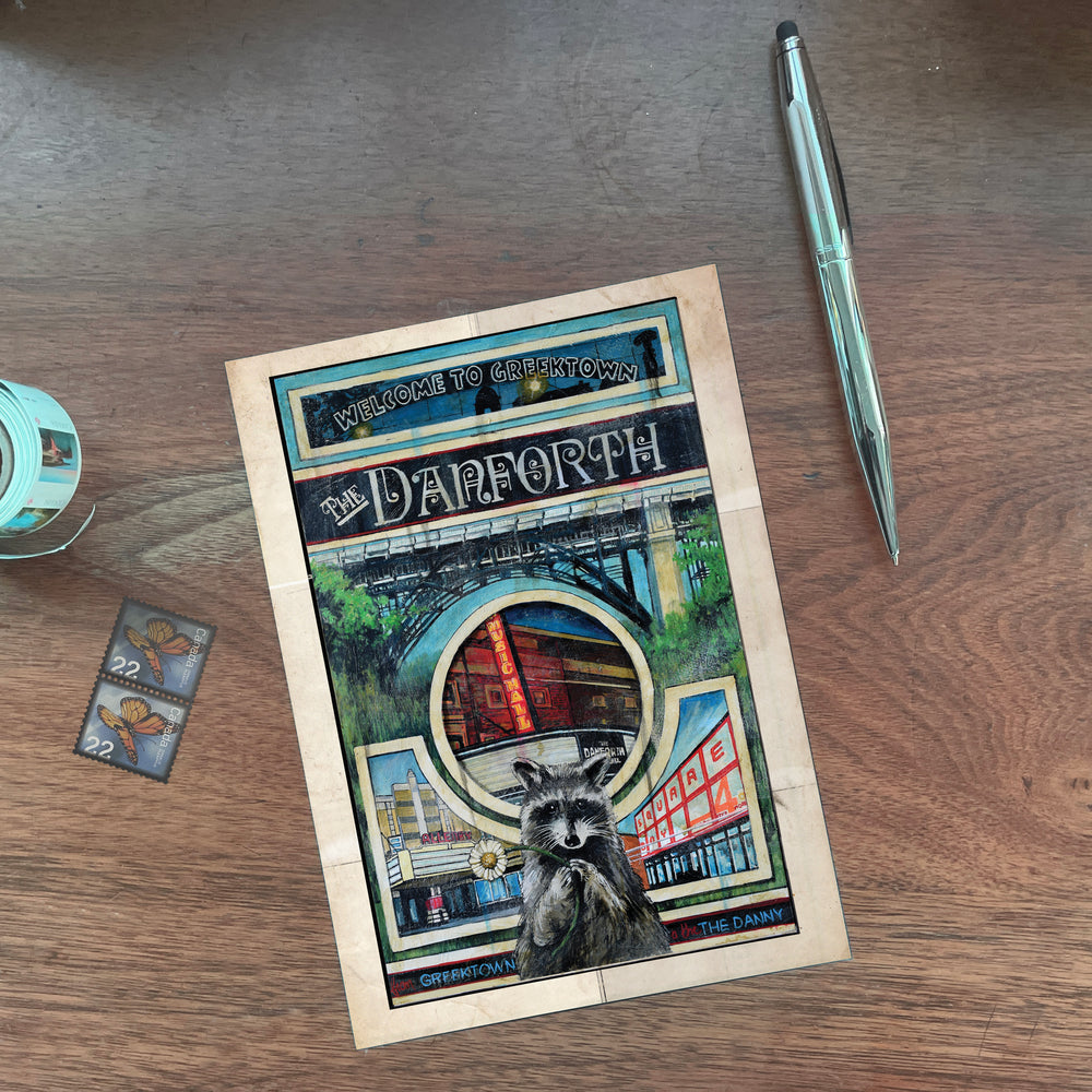 Danforth Welcome to Greektown Toronto Postcard by Rob Croxford against wooden table