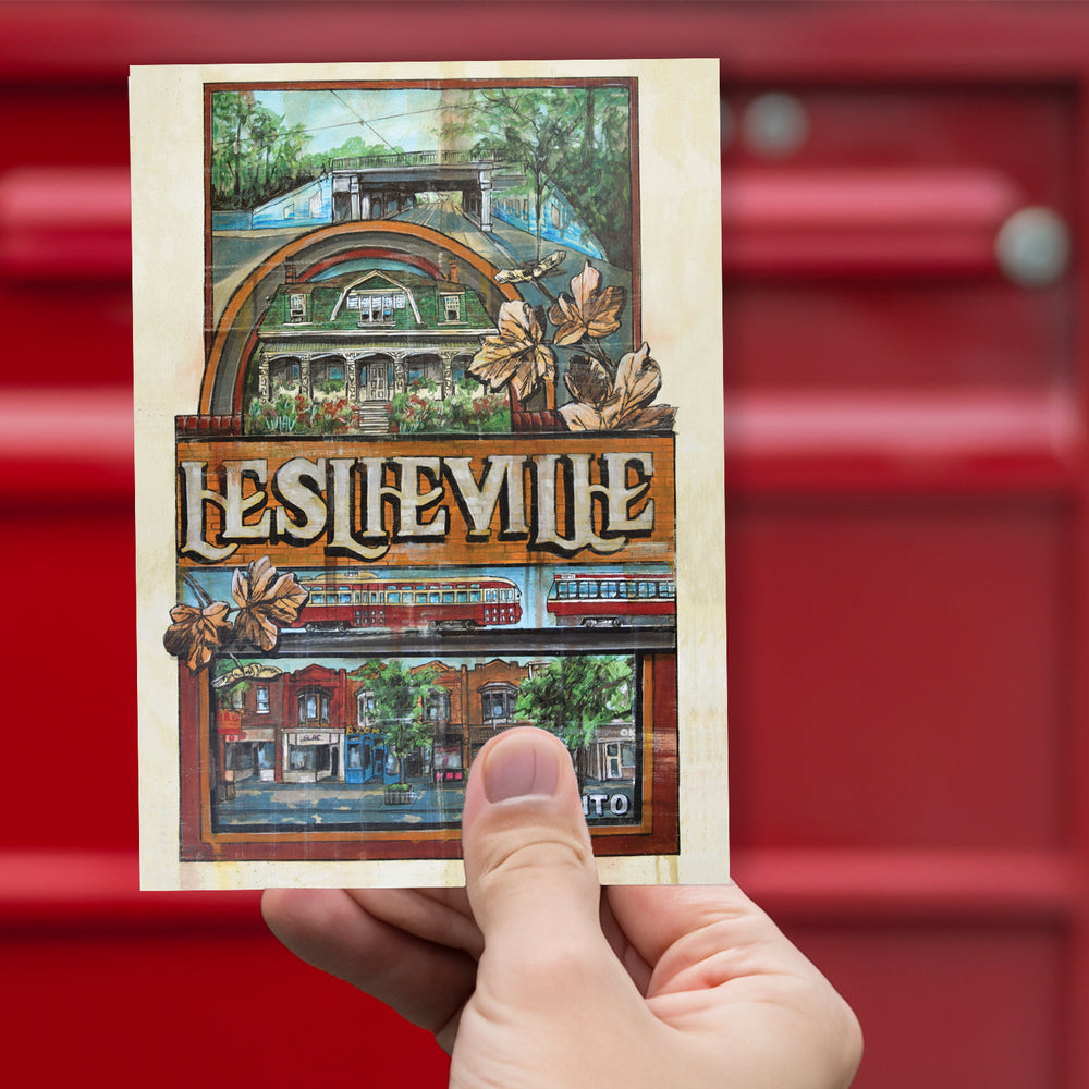 Leslieville Toronto Postcard by Rob Croxford held up against red mailbox