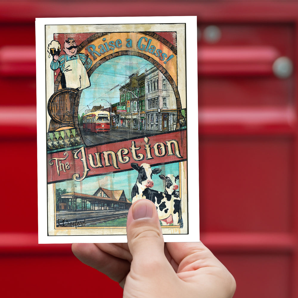 The Junction - Raise a Glass Toronto Postcard by Rob Croxford held up against a red mailbox