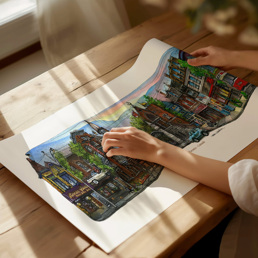 Beautiful illustration of Queen Street Bellwoods from Toronto Art Shop on a wooden desk, dappled in sunlight. 