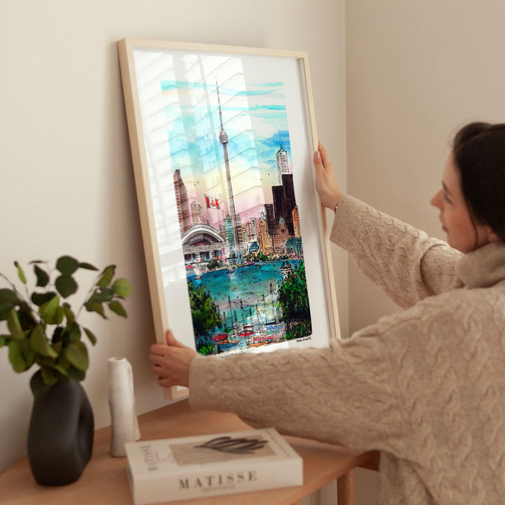 Pine Framed Toronto CN Tower Art Print being held against wall by a woman